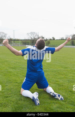 Deluso giocatore di football in blu seduti sul passo dopo aver perso Foto Stock