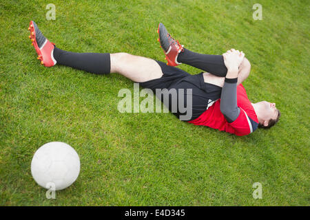 Giocatore di football in rosso giacente feriti sul campo Foto Stock