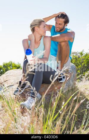 Montare il giovane prendendo una pausa al vertice sorridente ad ogni altro Foto Stock