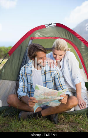 Attraente felice coppia seduta dalla loro tenda mappa di lettura Foto Stock