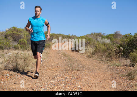 Athletic uomo jogging sul sentiero del paese Foto Stock