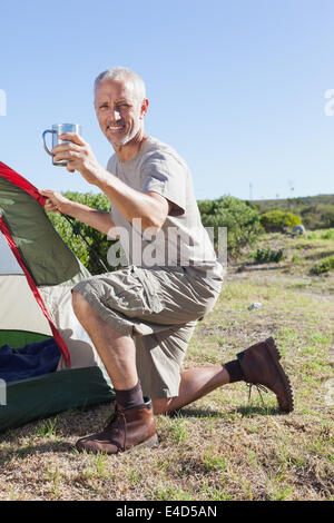 Happy camper impostando la sua tenda Foto Stock