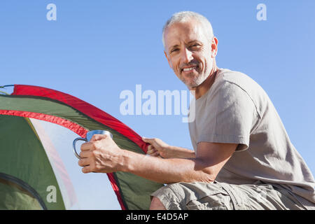 Happy camper impostando la sua tenda Foto Stock