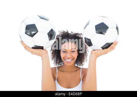 Pretty girl holding palloni da calcio e sorridente in telecamera Foto Stock