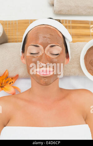 Sorridente brunette ottenendo un fango viso trattamento Foto Stock