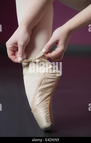 Ballerina di legatura del nastro sul suo balletto pantofole Foto Stock