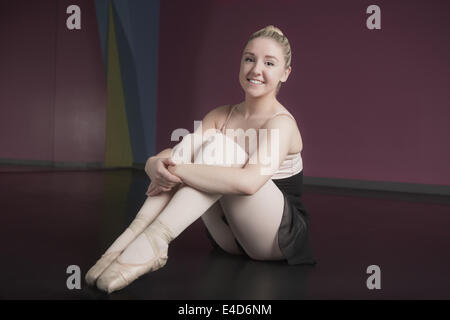 Pretty ballerina seduta e sorridente in telecamera Foto Stock