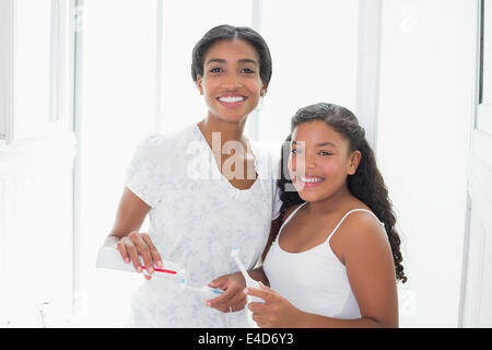 Bella madre spazzolare i suoi denti con sua figlia Foto Stock