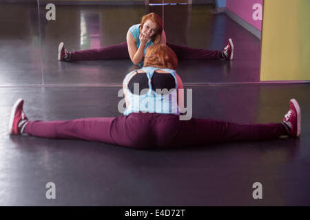 Piuttosto ballerino break facendo la divide in cerca dello specchio Foto Stock