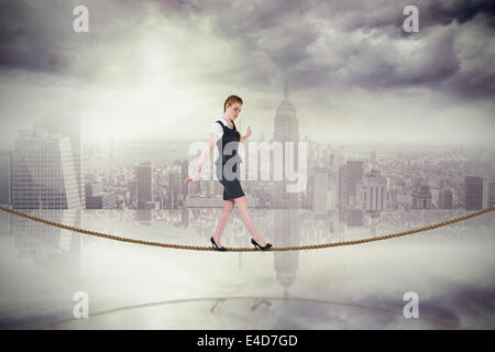 Immagine composita di imprenditrice facendo un atto di equilibrio su tightrope Foto Stock