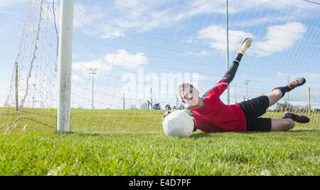 Il portiere in rosso effettuare un salvataggio Foto Stock