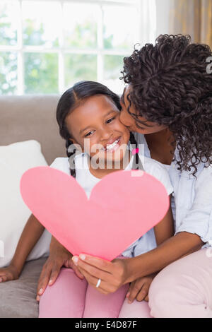 Piuttosto la madre seduta sul divano con la figlia di lettura scheda di cuore Foto Stock