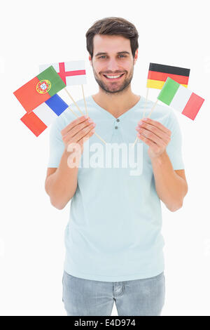 Uomo bello holding varie bandiere europee Foto Stock