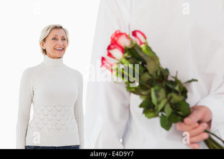 L'uomo nascondere mazzo di rose da donna più anziana Foto Stock