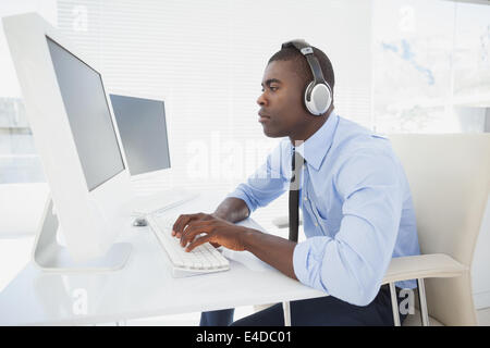 Imprenditore focalizzato al lavoro presso la sua scrivania ascolto di musica Foto Stock