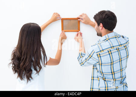 Felice coppia giovane mettendo su cornice immagine Foto Stock