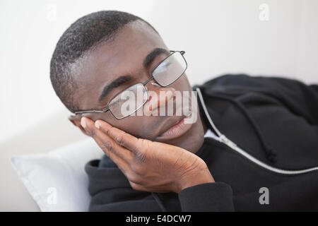 Uomo informale che dorme sul divano di casa con gli occhiali Foto Stock