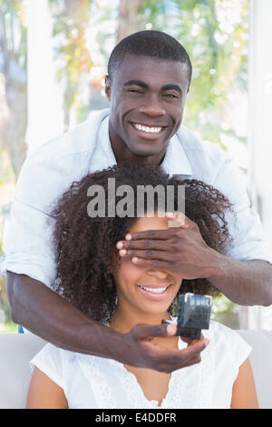 Uomo che copre gli occhi della sua fidanzata durante la preparazione della proposta Foto Stock