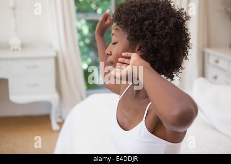 Bella donna seduta sul letto sbadigli Foto Stock