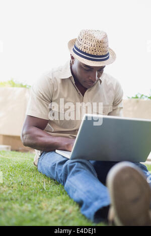 Uomo bello rilassarsi nel suo giardino utilizzando laptop Foto Stock