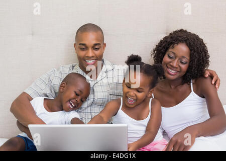 La famiglia felice utilizzando laptop insieme sul letto Foto Stock