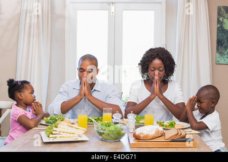 La famiglia felice dicendo grazia prima del pasto Foto Stock