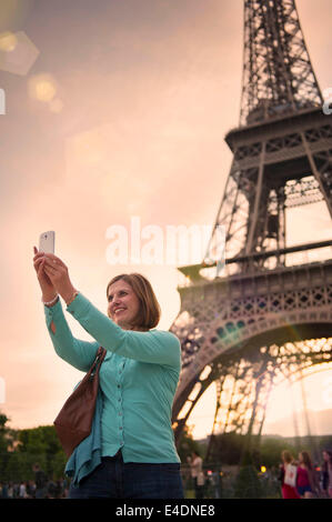 Donna matura prendendo un selfie con la Torre Eiffel a Parigi Foto Stock