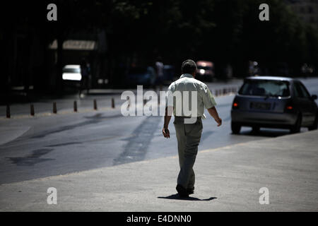 Salonicco, Grecia. 9 Luglio, 2014. Un uomo cammina nella strada vuota durante 24 ore di sciopero del settore pubblico ADEDY unione. La protesta contro la legge promossa dal governo per la valutazione dei funzionari pubblici e sostiene che questo porterà al licenziamento di funzionari. Salonicco, Grecia il 9 luglio 2014. Credito: Konstantinos Tsakalidis/Alamy Live News Foto Stock