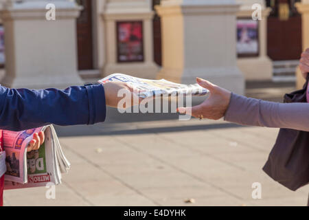 Quotidiano gratuito la distribuzione. Il distributore di consegnare un giornale Metro per una persona, Nottingham, Inghilterra, Regno Unito Foto Stock