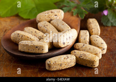 La vitamina a base di erbe e integrare le pillole con erbe sul cucchiaio di legno Foto Stock
