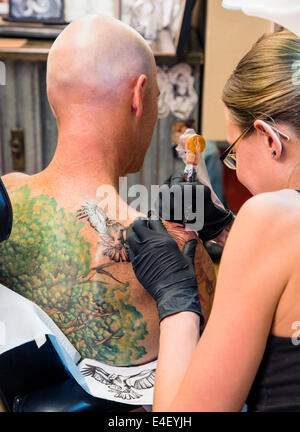 Donna tatuaggio un aquila sul retro di un uomo Foto Stock