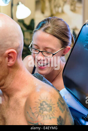 Donna tatuaggio un aquila sul retro di un uomo Foto Stock