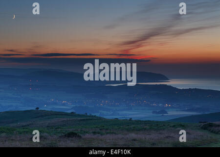 Vista dalla Quantocks al crepuscolo su una sera d'estate. Affacciato su Watchet, Williton e Minehead, Exmoor in distanza. Foto Stock