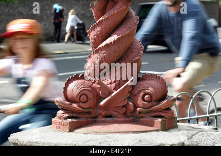 Close up intrecciano dolphin lampada standard ad un Preston Road entrata a Preston Park, Brighton (con i ciclisti passaggio). Foto Stock