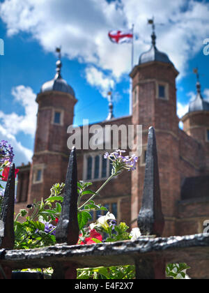 Storica la Gran Bretagna in estate con fiori in primo piano e la croce di San Giorgio a Abbot's Hospital Guildford Surrey UK Foto Stock