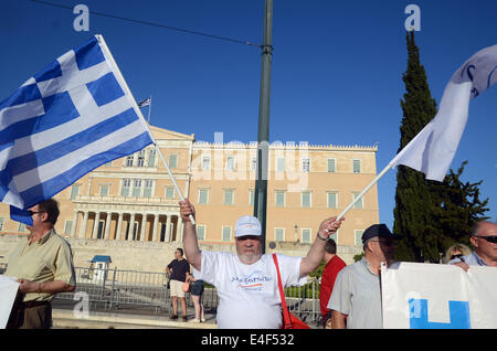 Il manifestante sorge di fronte al parlamento greco in piazza Syntagma tenendo una bandiera greca e le onde in aria durante la loro dimostrazione contro il governo di austerità. © George Panagakis/Pacific Press/Alamy Live News Foto Stock