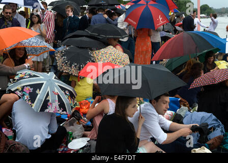 Pioggia pioggia pic-nic un inglese estate bagnato tempo 2010s Henley Royal Regatta folle di spettatori fiancheggiano le rive e riparano i loro ombrelloni. REGNO UNITO 2014 HOMER SYKES Foto Stock