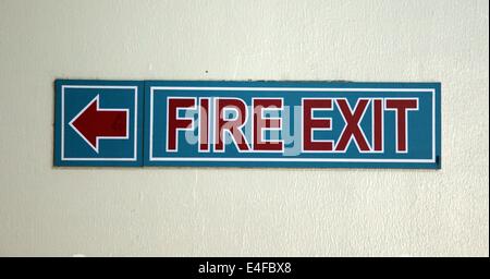 Si tratta di una foto di un segno della scheda che indicano la direzione del fuoco uscire. Sulla parete in rosso e blu Foto Stock