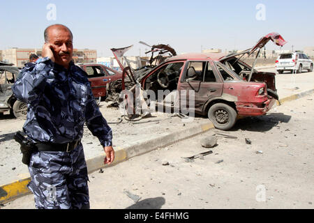 Kirkuk, Iraq. 10 Luglio, 2014. Persone ispezionare il sito di un attentato all'automobile intrappolata su vetture schierate in corrispondenza di una stazione di gas nella città di Kirkuk, nell Iraq del nord, 10 luglio 2014. L'attentato alla stazione di gas feriti sette persone qui il giovedì mattina. Credito: Dena Assad/Xinhua/Alamy Live News Foto Stock