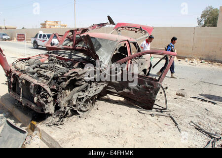 Kirkuk, Iraq. 10 Luglio, 2014. Persone ispezionare il sito di un attentato all'automobile intrappolata su vetture schierate in corrispondenza di una stazione di gas nella città di Kirkuk, nell Iraq del nord, 10 luglio 2014. L'attentato alla stazione di gas feriti sette persone qui il giovedì mattina. Credito: Dena Assad/Xinhua/Alamy Live News Foto Stock