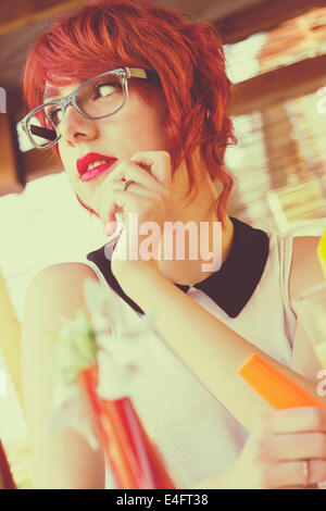 Carino hipster ragazza adolescente in una caffetteria, fantasticando, guardando lontano. In stile retrò, tonica immagine Foto Stock