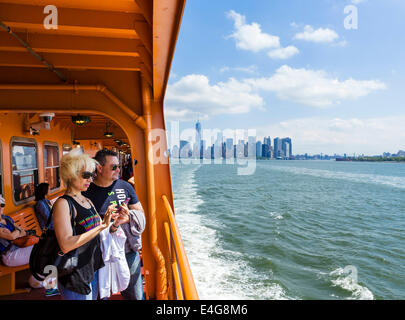 I passeggeri a bordo di Staten Island Ferry con la parte inferiore di Manhattan skyline dietro, New York City, NY, STATI UNITI D'AMERICA Foto Stock