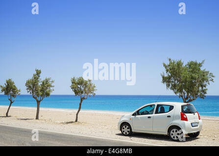 Una piccola auto a noleggio parcheggiato a fianco di una spiaggia deserta Foto Stock