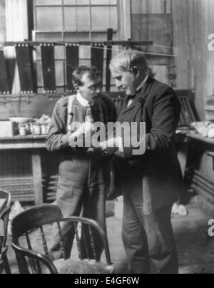 Thomas Alva Edison, in piedi nel suo laboratorio, discutendo di un problema con un operaio, circa 1906 Foto Stock