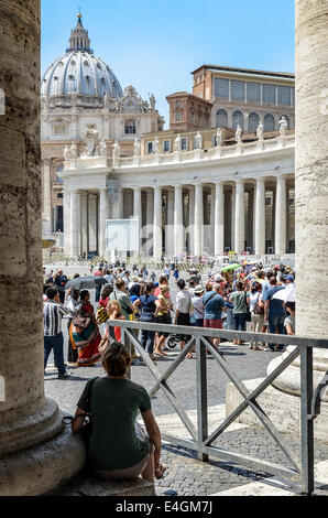 Una donna non identificato attende e orologi un folto gruppo di turisti davanti alla basilica di San Pietro. Foto Stock