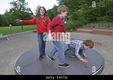 Bambini su un parco giochi rotonda Foto Stock