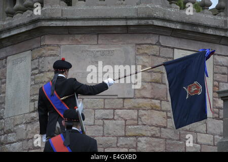 Jedburgh, Scottish Borders, UK. 7 Luglio, 2014. Jethart Callant del Festival 2014 Jethart Jack Callant Fraser abbassa il Burgh standard al Memoriale di guerra dopo la posa di corona, durante il giorno del Festival. La Scottish comune festival di equitazione sono eventi annuali in cui i locali cavalcare su cavalli a ceremonially controllare e proteggere le terre comuni della loro città. Credito: Rob grigio/Alamy Live News Foto Stock