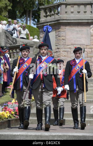 Jedburgh, Scottish Borders, UK. 7 Luglio, 2014. Jethart Callant del Festival 2014 Jethart Jack Callant Fraser affiancato dal suo lato sinistro e destro uomini presso il Memoriale di guerra dopo la posa di corona, durante il giorno del Festival. La Scottish comune festival di equitazione sono eventi annuali in cui i locali cavalcare su cavalli a ceremonially controllare e proteggere le terre comuni della loro città. Credito: Rob grigio/Alamy Live News Foto Stock