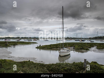 Paesaggio di moody del cielo della sera oltre la bassa marea marine pieno di barche Foto Stock