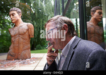 Artista Stephan Balkenhol sorge accanto alla sua scultura in legno "Tempre piu' nel parco della scultura a Wuppertal, Germania, 11 luglio 2014. Balkenhols' importanti opere, che è un professore presso l'Karslruhe Art Academy, sono sul display fino al 12 Ottobre. Foto: BERND THISSEN/dpa Foto Stock